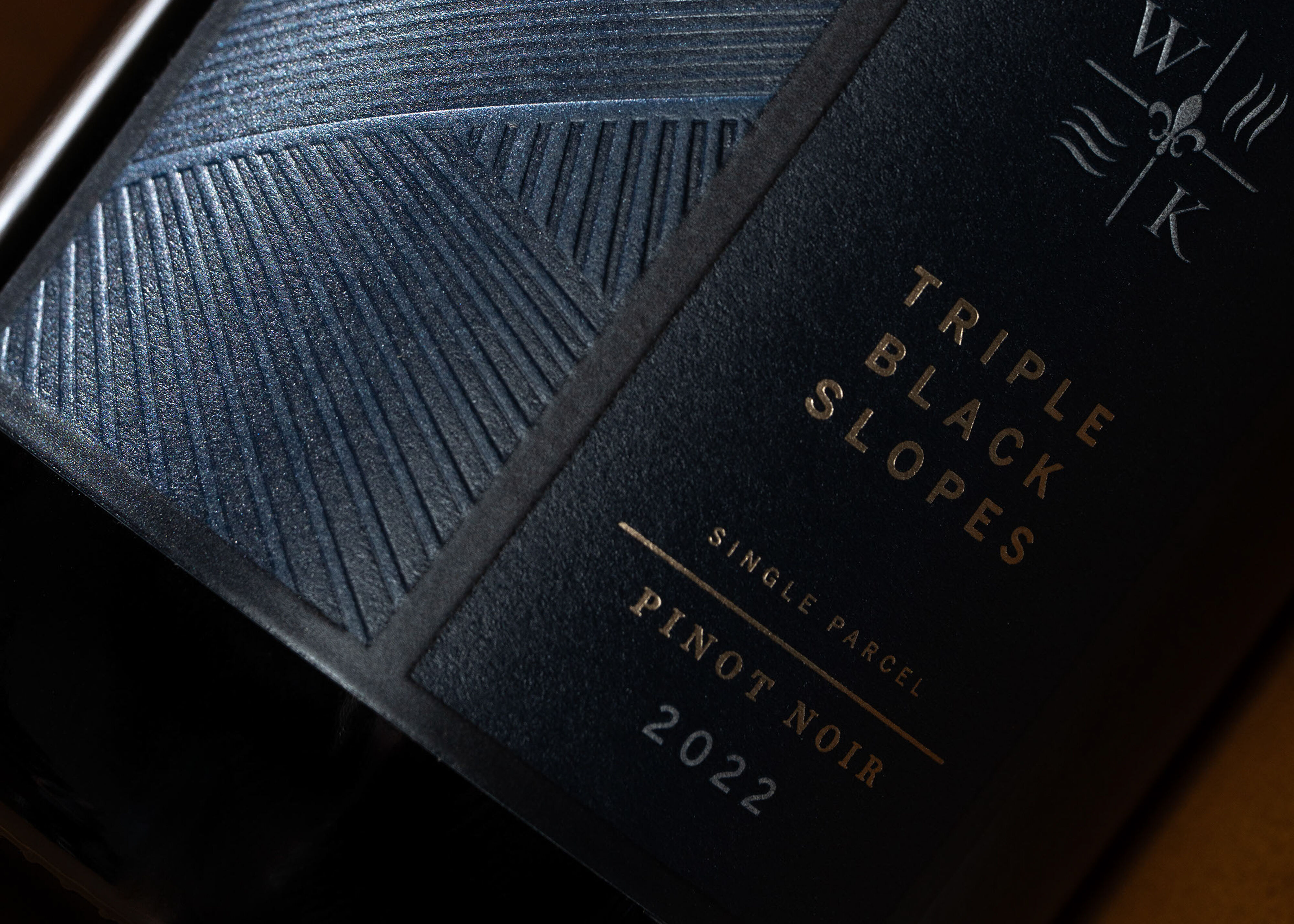 Seven bottles of WillaKenzie Estate Pinot Noir standing on a counter.